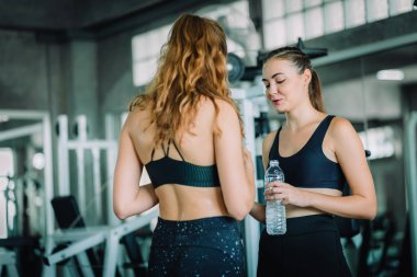 Güzel genç kadın sporcular spor olarak çalışma sonra fitness giysilerle rahatlatıcı uygun. Şişe suda Holding ayakta ve fitness app smartphone kullanarak iki kadın. Spor, yaşam kavramı, sağlıklı.