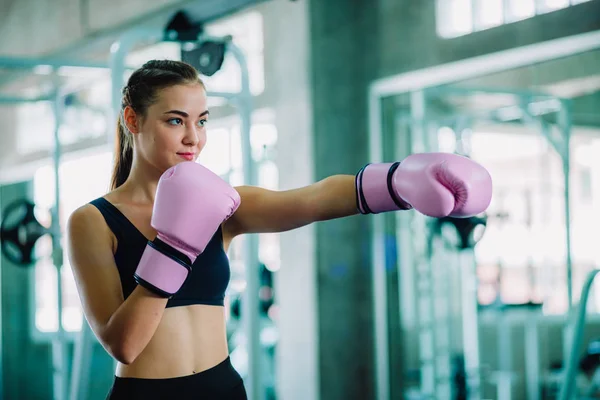 Fit beautiful woman boxer hitting a huge punching bag exercise class in a gym. Boxer woman making direct hit dynamic movement. Healthy, sports, lifestyle, Fitness, workout concept. With copy space.