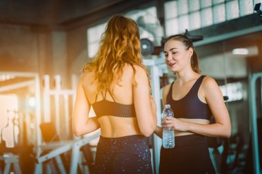 Güzel genç kadın sporcular spor olarak çalışma sonra fitness giysilerle rahatlatıcı uygun. Şişe suda Holding ayakta ve fitness app smartphone kullanarak iki kadın. Spor, yaşam kavramı, sağlıklı.