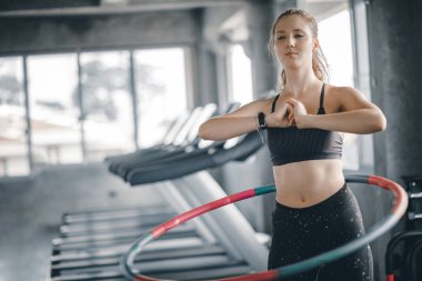 Güzel beyaz genç kadının adım bel ileriye doğru duruş doldurma hula hoop yapması. Genç kadın bir spor salonunda bir egzersiz dersi sırasında hula hoop yapıyor. Sağlıklı spor yaşam tarzı, Fitness, sağlıklı kavramı.