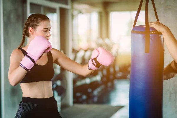 Fit beautiful woman boxer hitting a huge punching bag exercise class in a gym. Boxer woman making direct hit dynamic movement. Healthy, sport, lifestyle, Fitness, workout concept. With copy space.