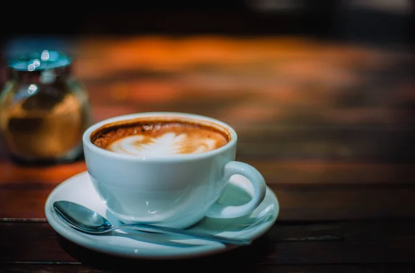 Sıcak kahve latte kapuçino sarmal köpük kahve dükkanı Cafe vintage renk tonu filtre arka plan ile ahşap masa üzerinde. Metniniz için kopya alanı ile.