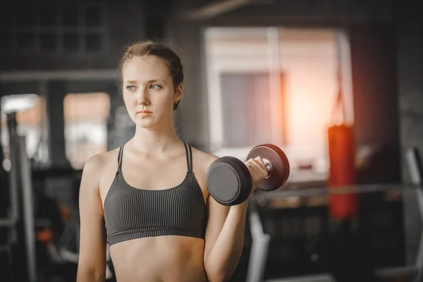 スポーツウェアのカメラで美しい若い女性白人ポーズに合わせて 若い女性は ジムで運動クラス中にダンベルを保持しています 健全なスポーツ ライフ スタイル フィットネスの概念 — ストック写真