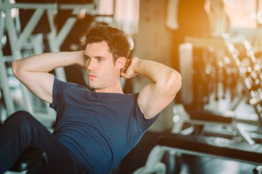 Uygun beyaz yakışıklı adam otur spor giyim makine üzerinde. Genç adam otur dayanıklılık egzersiz fitness eğitim salonunda, kendi çekirdek karın kasları. Sağlıklı, spor, yaşam tarzı, Fitness kavramı