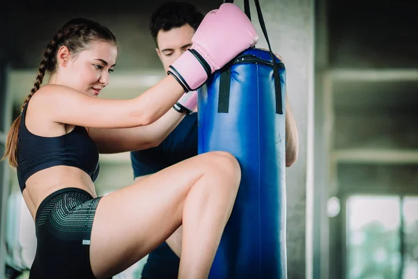 Fit beautiful woman boxer hitting a huge punching bag exercise class in a gym. Boxer woman making direct hit dynamic movement. Healthy, sport, lifestyle, Fitness, workout concept. With copy space.