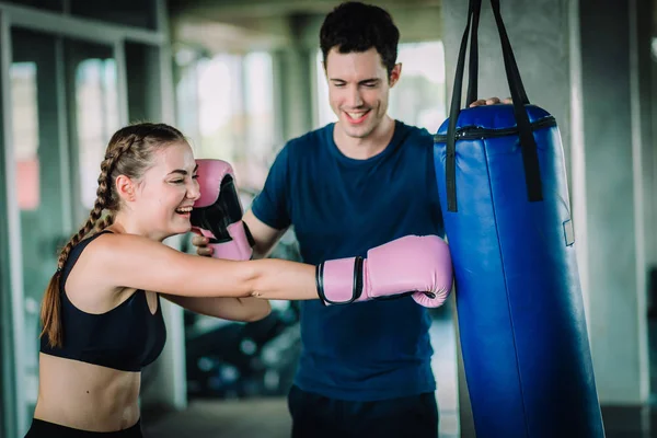 Fit beautiful woman boxer hitting a huge punching bag exercise class in a gym. Boxer woman making direct hit dynamic movement. Healthy, sport, lifestyle, Fitness, workout concept. With copy space.