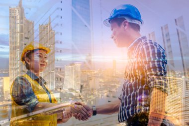 Çift pozlama mühendislik ve inşaat konsepti. Endüstriyel mühendis güvenlik kaskı takıyor. Mimari proje için el sıkışıyor. Partnerle çalışıyor ve şehir planıyla gülümsüyor..