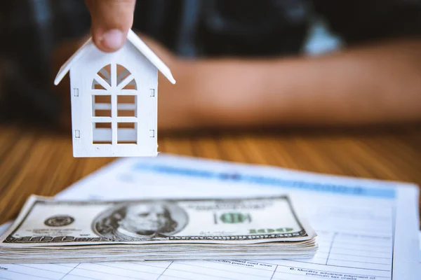 Handhållen modell vit hus på dollar sedel. Försäkrings- och fastighetsinvesteringskoncept. — Stockfoto