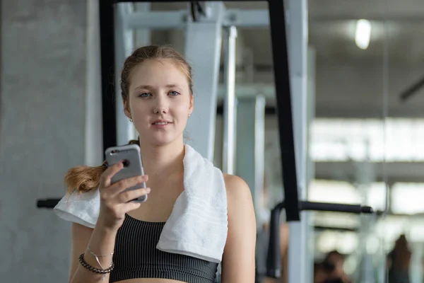 Happy Young attractive women fitness using smartphone resting in gym during morning exercise. Relaxation after hard workout in gym. Healthy sports lifestyle, Fitness concept. 스톡 사진