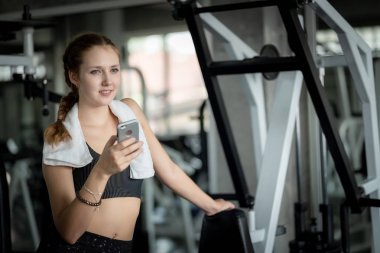 Genç ve çekici kadınlar spor salonunda spor yaparken akıllı telefon kullanıyor. Spor salonunda sıkı çalıştıktan sonra rahatlama. Sağlıklı spor yaşam tarzı, spor konsepti.