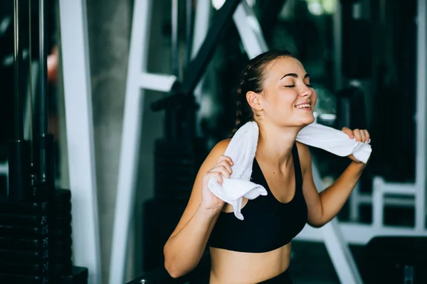 Junge attraktive Frau kaukasischen sitzt und mit Handtuch den Schweiß abwischen. Entspannung nach hartem Training im Fitnessstudio. Fitnesskonzept, gesund, Sport, Lebensstil — Stockfoto