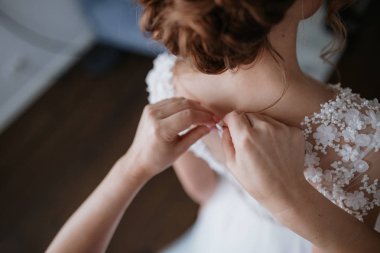 Düğün sabahı. Gelinlik giymiş gelinin yan görüntüsü. Nedimeler gelini düğün gününe hazırlıyorlar..