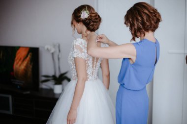 Düğün sabahı. Gelinlik giymiş gelinin yan görüntüsü. Nedimeler gelini düğün gününe hazırlıyorlar..