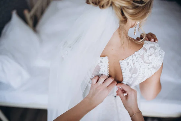 Ajuste del vestido de novia, parte posterior del vestido de novia con encaje o bordado. Dama de honor sujetar botones en el vestido en la preparación de la boda por la mañana . —  Fotos de Stock