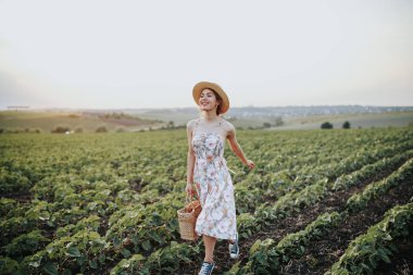 Açık yaz sepet çilek, hasır şapka ile genç kız portresi. Ülke yolda bir kız arkadan görünüm. Doğa arka plan, kırsal manzara, yeşil çayır, ülke stil