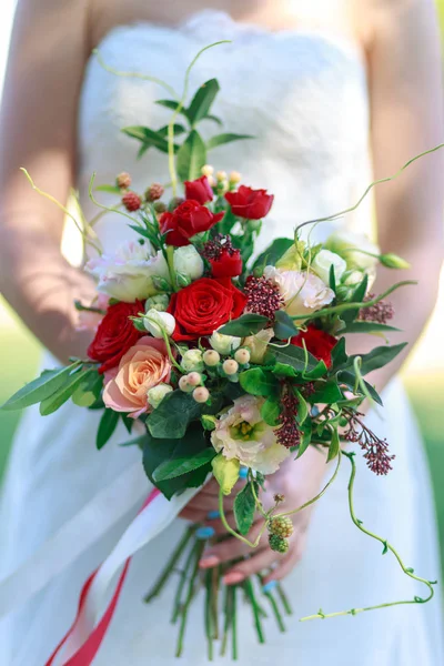 Wedding bouquet of flowers including Red hypericum, Roses, Lilies of the valley, mini Roses, Seeded Eucalyptus, Astilbe, Scabiosa, Pieris, and ivy