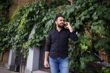 Bir sakallı bir adamın çıkıp telefonla konuşuyor