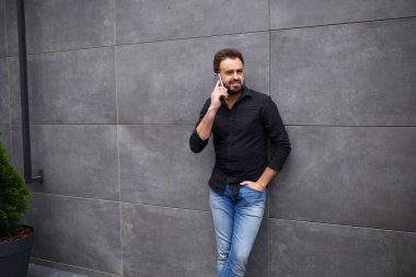 Bir sakallı bir adamın çıkıp telefonla konuşuyor