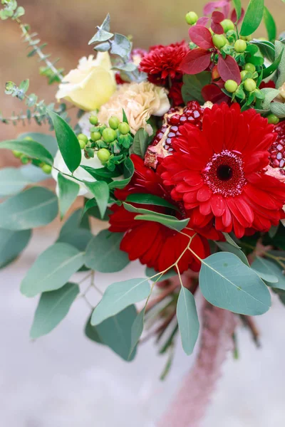 Wedding bouquet of flowers including Red hypericum, Roses, Lilies of the valley, mini Roses, Seeded Eucalyptus, Astilbe, Scabiosa, Pieris, and ivy