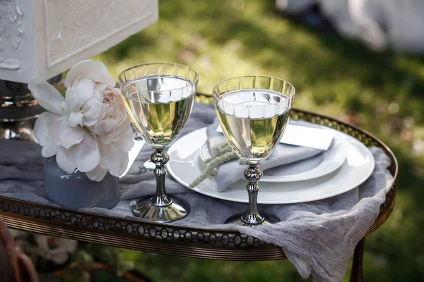 Mariage. Un banquet. Les chaises et la table ronde pour les invités, servis avec des couverts, des fleurs de verdure et de la vaisselle et recouverts d'une nappe blanche — Photo