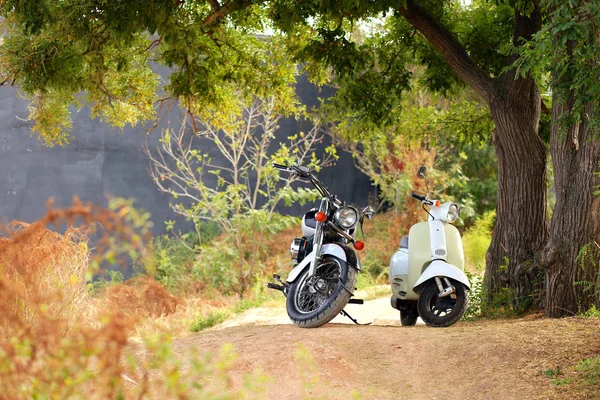 Ročník černá motocykl stojí v blízkosti bílé motorce v paprscích slunečního světla. Boční pohled — Stock fotografie