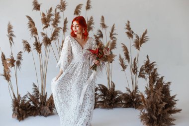 Düğün içeriği - bir dekorasyon ile beyaz bir arka plan üzerinde duran bir stüdyoda genç güzel kızıl saçlı kız yakın çekim Portre. Kopyalama alanı