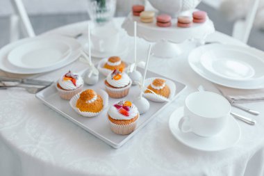 Yaratıcı bahar kompozisyonu. Zarif tatlı tatlı makarna, çay veya kahve fincan ve güzel pastel renkli bej ve beyaz mermer arka plan üzerinde yaşayan mercan çiçekleri buket