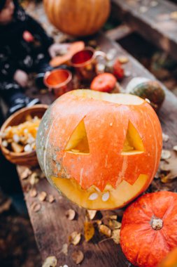 Ahşap arka plan üst görünümünde kabaklar arasında oyulmuş gülümseyen halloween kabak kafası