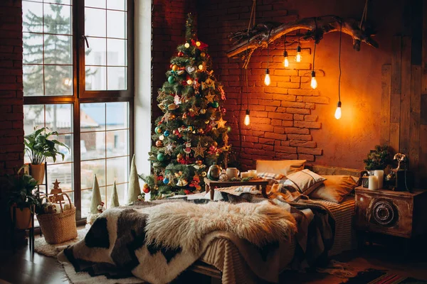 Süslü Noel ağacı ve çelengi olan, tavan arası tarzı geniş, beyaz bir yatak odası.