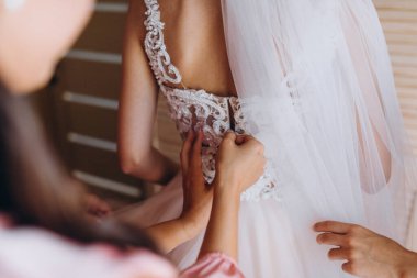 Düğün sabahı. Gelinlik giymiş gelinin yan görüntüsü. Nedimeler gelini düğün gününe hazırlıyorlar..