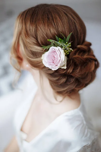 young beautiful bride hairstyle with fresh flowers .