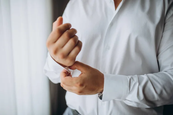man buttons shirt, a man in a white shirt, hands of a man close-up, businessman puts on a suit.