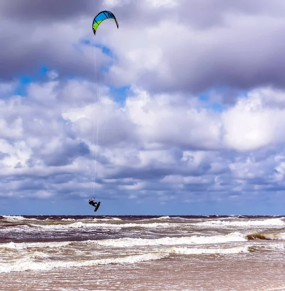 Baltık Denizi dalgalar bulutlu gökyüzü altında Venspils beach yakınındaki üzerindeki hava yüksek atlama Kitesurfer. Eğlenceli denizin içinde. Aşırı spor kitesurfing.