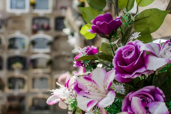 Bouquet of purple artificial flowers against the burial niches at Poblenou Cemetery in Barcelona, Spain. Spanish cemeteries have a system where a coffin is inserted in niche, rather than ground.