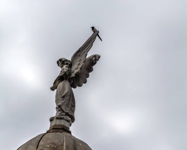 Barcelona, İspanya - 10 Mayıs 2018: Melek heykel ve bir magpie Poblenou mezarlığı bulutlu gökyüzü karşı. Poblenou Mezarlığı, bugün ev sahipliği inanılmaz heykeller, haunting, henüz güzel olduğunu.