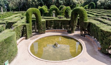 Barcelona, İspanya - 10 Mayıs 2018: Labirent Park Horta labirent çıkışında küçük dairesel gölet. Eros ve selvi kemer Merkez heykeli arka planda görünür.