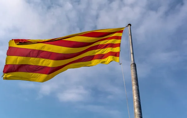 Mavi gökyüzü karşı esintiyle Catalonia sallayarak bayrak. Bayrak Senyera (Katalanca bayrak) denir ve sarı zemin üzerinde dört kırmızı çizgiler oluşur. Katalanca ulus ve kültür temsil eder