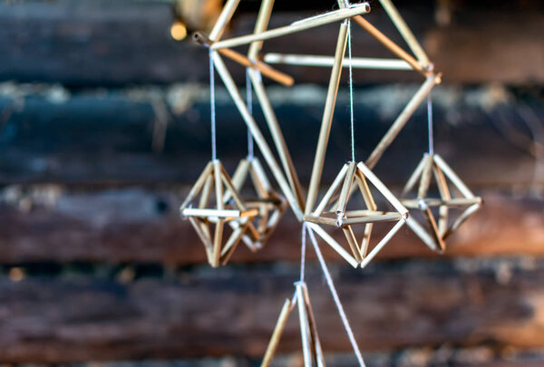 Latvian Puzurs hanging in the dark log hut. Puzurs is traditional Latvian room decoration made of reeds or straws. It is solstice symbol similar to Finnish Himmeli and Lithuanian Siaudinis Sodas.