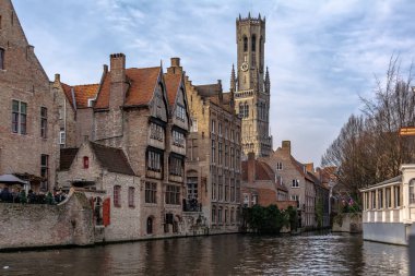 Bruges, Belçika - 15 Aralık 2018: Klasik ortaçağ binaları ve arka planda Bruges Belfry ile Bruges Rozenhoedkaai (Tespih Quay) kanal. Güneşli günde Tespih Rıhtımı.