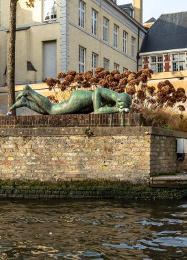 Bruges, Belçika - 15 Aralık 2018: Kanalın yanında yatan ve suya bakan çıplak kadın heykeli. Kanal resmi.