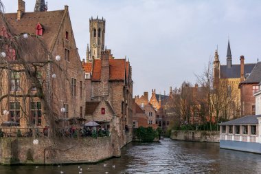 Arka planda klasik ortaçağ binaları ve Bruges Belfry ile Bruges Rozenhoedkaai (Tespih Rıhtımı) kanal. Güneşli günde Tespih Rıhtımı.