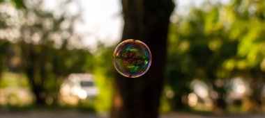 Renkli yarı saydam sabun köpüğü ağaçların yansıması ile havada yüzen, gökyüzü ve güneşli akşam bina. Sabun kabarcıkları closeup ile Doğa arka plan. Yumuşak rüya gibi görüntü.