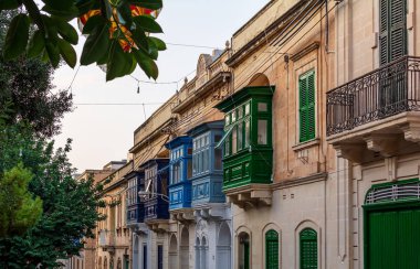 Malta 'nın Sliema kentindeki geleneksel ahşap balkonlu ev cephesi akşam güneşiyle turuncuya boyanmış. Otantik Malta şehir sahnesi.