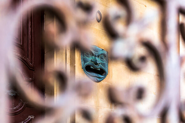 Historic vintage face shaped mailbox at residential building shoot from behind iron ornate fence in Sliema, Malta.