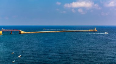 Malta, Valletta 'daki Saint Elmo Kalesi' nin ön kıyılarından Büyük Liman 'ın girişindeki dalgakırana kadar turkuaz Akdeniz suyunda Kızıl St Elmo Köprüsü..