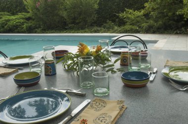 Granit tablo farklı renkli tabaklar, yeşil gözlük ve gümüş çatal bıçak takımı ile bir öğle yemeği için havuz başında ayarlayın