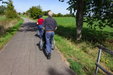 üst düzey adam tekerlekli sandalye ve lady bikeway üzerinde yürüyüş güneşli yaz gün içinde Alman kırsal üzerinde sexpartyn iken sahip yıldızlar