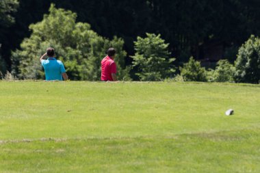 çok güneşli bir Güney Almanya'da golf çim yeşil gördüğünüz ve bayrak ve oyuncular ve kum alanları ve golfplace çevresinde yolu olan mahkeme