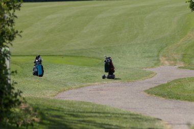 çok güneşli bir Güney Almanya'da golf çim yeşil gördüğünüz ve bayrak ve oyuncular ve kum alanları ve golfplace çevresinde yolu olan mahkeme