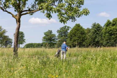 çok güneşli bir Güney Almanya'da golf çim yeşil gördüğünüz ve bayrak ve oyuncular ve kum alanları ve golfplace çevresinde yolu olan mahkeme